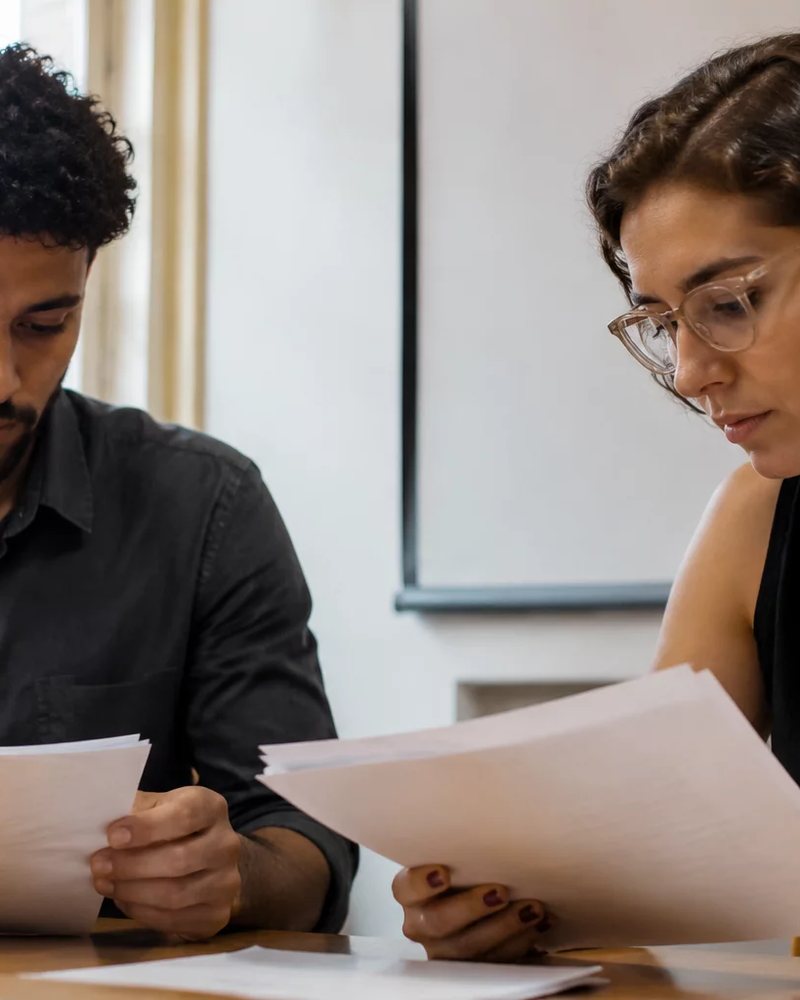 Duas pessoas discutem de pé entre estantes de biblioteca, cada uma defendendo o seu ponto